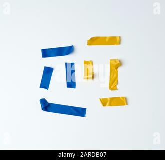 set of torn multicolored rubber pieces of electrical tape glued to a white background, close up Stock Photo