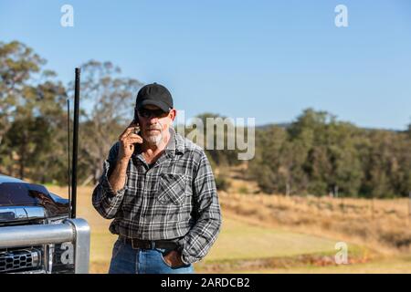 Man on mobile phone overlooking paddock, next to truck with antennas Stock Photo