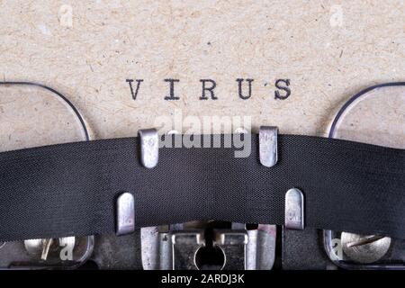 The word virus written in typewriter font. The inscription in the old style on gray paper. Grey background. Stock Photo