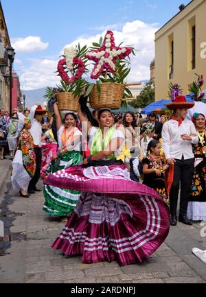 Woman dancing in flowing traditional outfit with flower basket Part of Traditional parade (Calenda de Bodas) on the streets of Oaxaca. Stock Photo