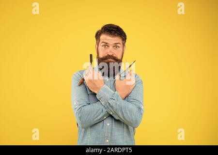 Retro barbershop. Hipster with tools. Designing haircut. Fresh hairstyle. Barbershop concept. Barbershop salon. Personal stylist. Vintage barber. Bearded man hold razor and scissors. Classic values. Stock Photo