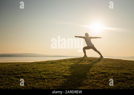 The young man warmed up before running during the sunrise on the lake.