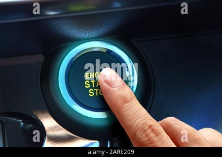 Finger pressing the start or stop engine button in close up. Stock Photo