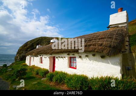 Manx Cottage with thatched roof by the sea Stock Photo