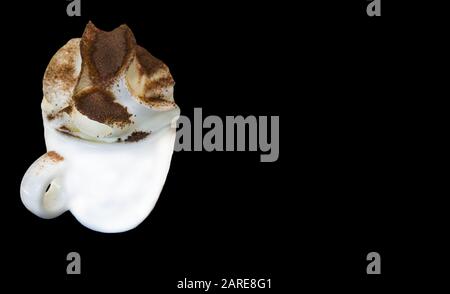 Cup of coffee with cream and chocolate topping under the lights against a black background Stock Photo