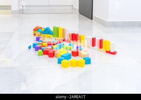 Different color and shape wooden toy building blocks in home on grey tiles floor. Stock Photo
