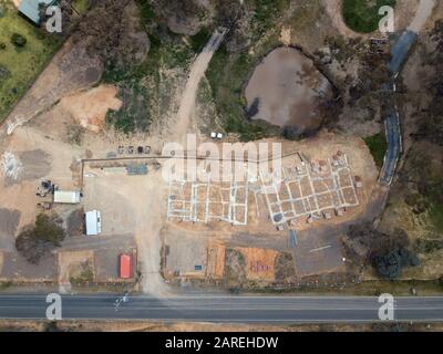 Subdivision homes and planned eco housing development aerial view with concrete formwork, trees and asphalt road in Victoria, Australia. Stock Photo