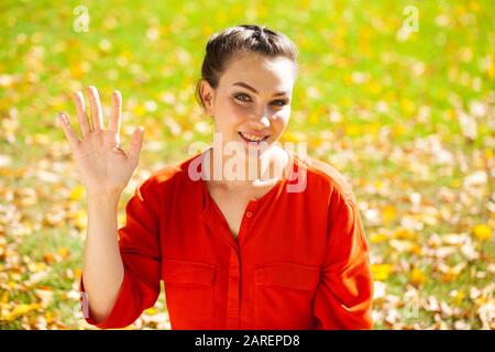Portrait close up of young beautiful brunette woman in red shirt, autumn park outdoors Stock Photo