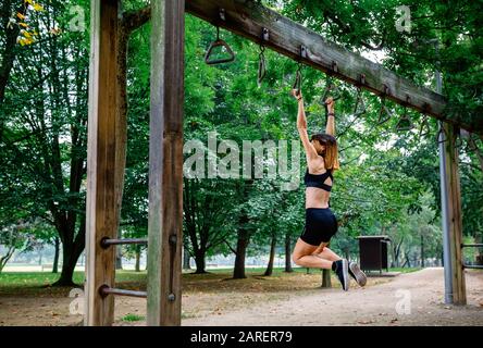 Woman doing monkey exercises on rings Stock Photo