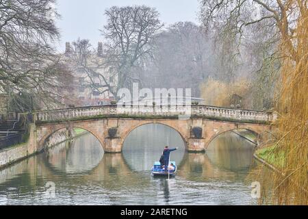 Chinese tourists punted under the bridge over the river Cam at Clare college, university of Cambridge, England, on a misty winter day. Stock Photo