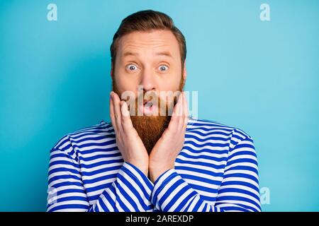 Portrait of astonished man listen secret scream touch hands chin wear good look outfit isolated over blue color background Stock Photo