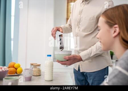 Daughter looking at plate with granola in her fathers hands. Stock Photo