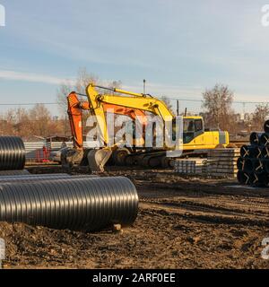 Two yellow excavator on construction site against blue sky. construction of pipelines for domestic water supply. Stock Photo
