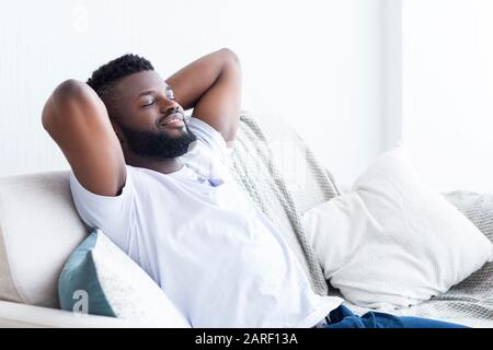 Relaxed african american man resting at home on sofa Stock Photo