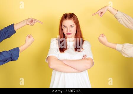 Blaming. Caucasian young woman's portrait on yellow studio background, too much tasks. Social ladder, psychology, mental health. Concept of office working, business, self management, planning. Stock Photo
