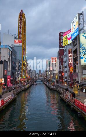 OSAKA, JAPAN - OCTOBER 14, 2019: The view of the Dotonbori canal in the evening colorful lights with its huge yellow Ferris wheel of Don Quijote store Stock Photo