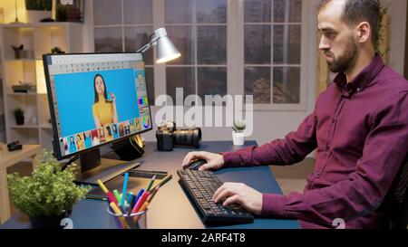 Male photographer edits photos in creative office. Software for retouching. Stock Photo