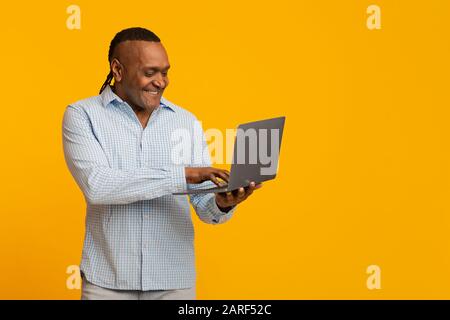 Modern mature african man surfing on internet on laptop Stock Photo