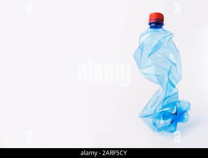Crumpled or squashed blue plastic bottle isolated on white Stock Photo