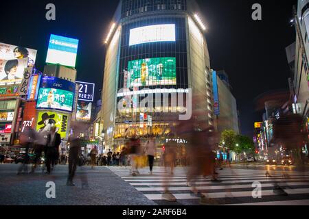 Tokyo, Japan - 27 June 2016: Slow shutter speed night shot of pedestrians crossing the street at the Shibuya Crossing intersection. In Tokyo, Japan. Stock Photo