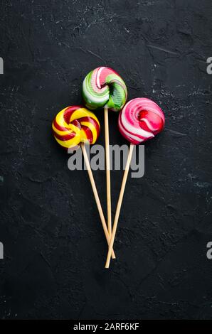 Caramel candies and lollipops. Colored candies. On a black background. Top view. free copying space. Stock Photo