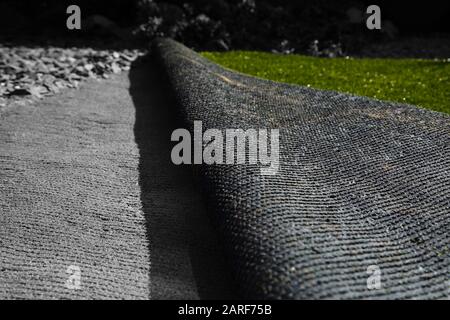 Laying artificial grass turf onto sand in a back garden yard. With selective colour Stock Photo