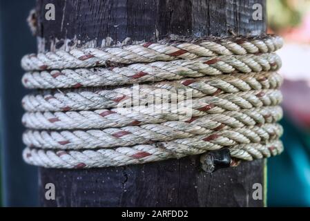 This unique photo shows a white red rope wrapped around a wooden post. The picture was taken in Hua Hin Thailand Stock Photo