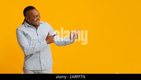 Smiling mature african man pointing aside at copy space Stock Photo
