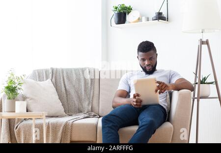 Young african man browsing on digital tablet at home Stock Photo