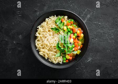 Asian soup with noodles and vegetables in a bowl, with toast bread. Dietary food. Top view. Free copy space. Stock Photo