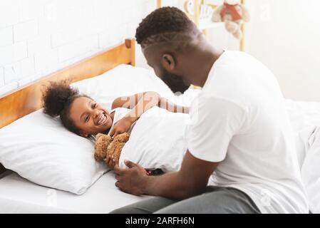 Dad waking up his little cute daughter in the morning Stock Photo