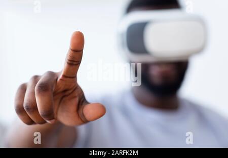 African guy in vr headset pushing virtual button on camera Stock Photo