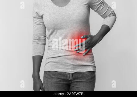 Black and white cropped photo of woman rubbing left side Stock Photo