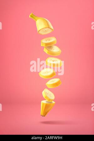 Flying fresh ripe banana cut into slices on pink background Stock Photo