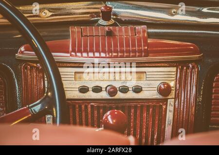 Retro styled image of an old car radio inside a red classic car Stock Photo