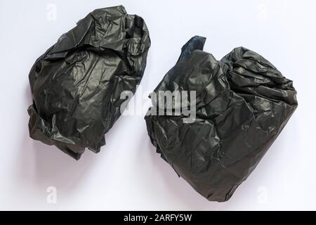 Two scrunched up balls of black tissue paper from inside shoes boots isolated on white background Stock Photo