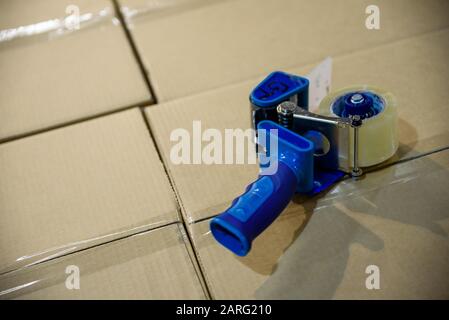 Packaging tape gun dispenser on a cardboard box Stock Photo