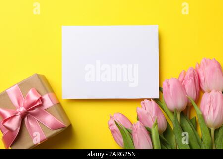 Pink tulips, gift box and empty place on yellow background, space for text Stock Photo