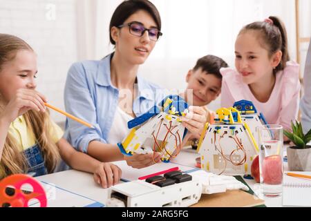 Pupils and teacher constructing robots together in class Stock Photo