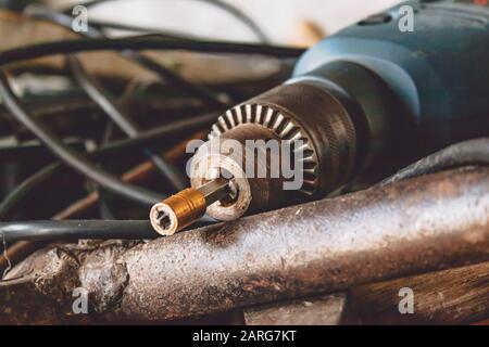 An electric drill lies on a pile of cable and hammers. Tools for the job. Stock Photo