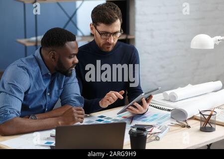 Multiracial engineer team working in office with tablet PC. Architects select colors for building using color swatches, sketching and planning Stock Photo