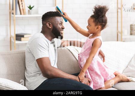 Little girl brushing her young dad's hair Stock Photo