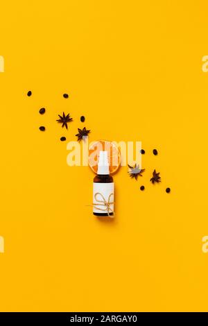 Natural body care. Glass bottle for perfume, oil or body lotion lying on slice of orange and surrounded by cinnamon, coffee beans, natural soap and sp Stock Photo