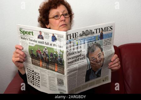 Woman reading a copy of The Times newspaper Stock Photo
