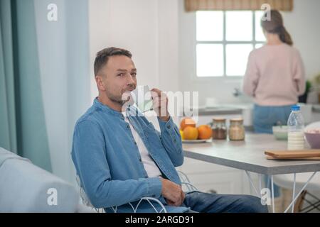 Father drinking tea sitting at a table in the kitchen. Stock Photo