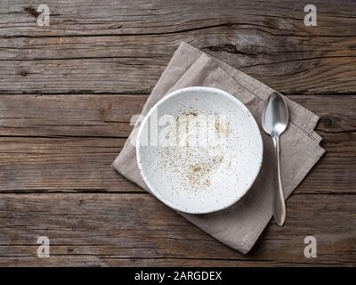 empty soup plate and spoon on rustic gray wooden table, linen napkin, top view Stock Photo