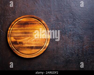 Empty round dark brown wood cutting Board on dark brown stone background, top view, copy space Stock Photo