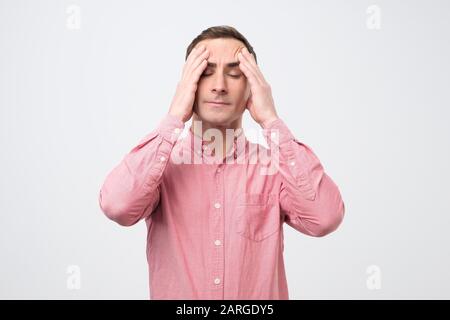 Worried young italian man suffering from headache. Studio shot Stock Photo