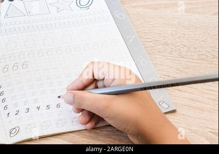 Schoolboy writing numbers close up. Pencil in the hands of children. The boy is writing. Stock Photo