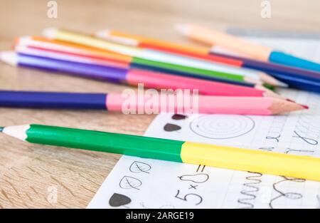 Colored pencils scattered on a school notebook. Close-up. Stock Photo